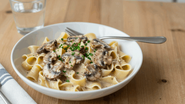 Teller mit Bandnudeln in cremiger Champignonrahmsauce und Petersilie