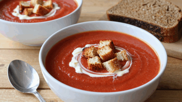 Teller cremige Tomatensuppe mit goldbraunen Röstbrotwürfeln