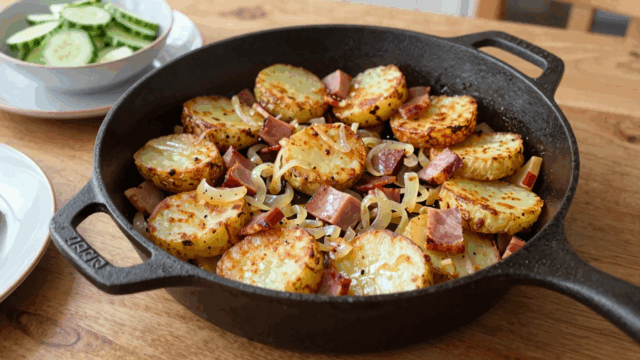 Knusprige Bratkartoffeln mit Schinkenwürfeln und Zwiebeln in der Eisenpfanne