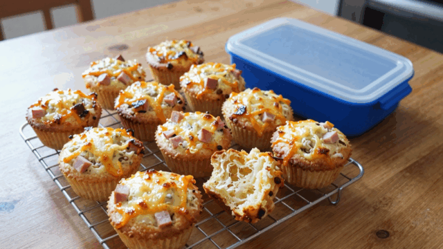 Herzhafte Käse-Schinken-Muffins auf dem Kuchengitter, einer aufgebrochen