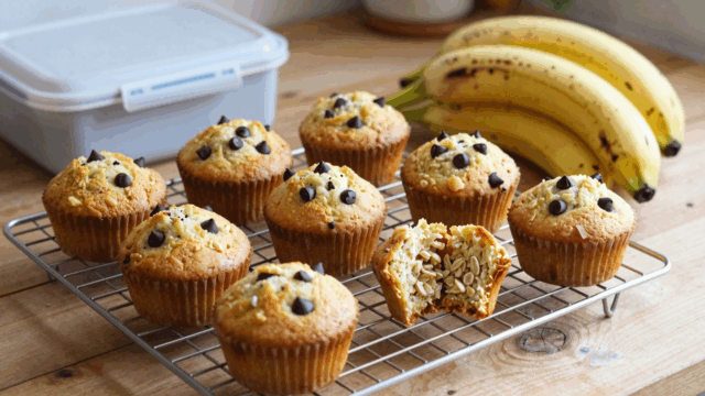 Bananenmuffins mit Schokotropfen auf dem Kuchengitter, einer aufgebrochen
