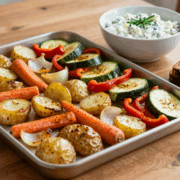 Blech mit geröstetem Gemüse, daneben eine Schüssel Kräuterquark und Brot