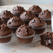 Zwölf Schokomuffins auf dem Gitter, einer aufgebrochen mit geschmolzenen Schokoladenstücken