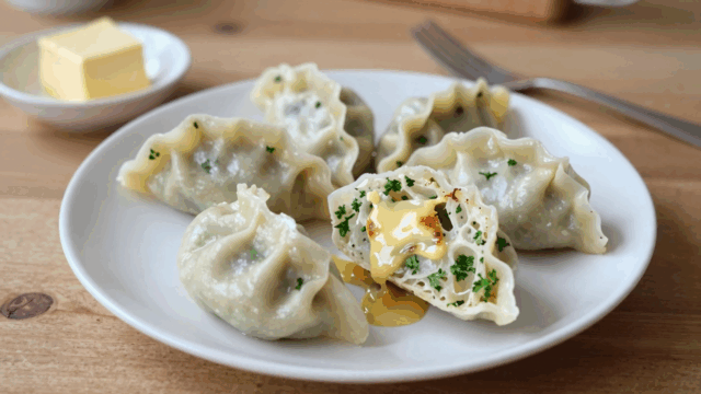 Semmelknödel aus alten Brötchen auf einem weißen Teller mit brauner Butter