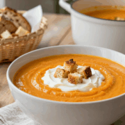 Sämige Möhrensuppe mit Schmand und Croutons aus altem Brot in einer tiefen Schüssel